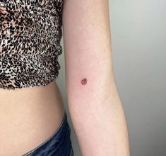 a small red dot tattoo on the left inner arm and lower half of the arm