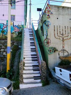 there are many stairs painted on the side of this building and cars parked in front