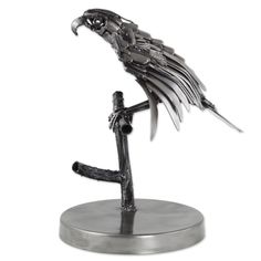 a metal figurine of a bird on a branch with its wings spread out