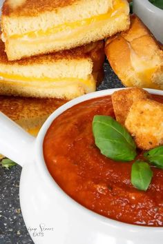 grilled cheese sandwiches and tomato soup on a plate with basil garnishes