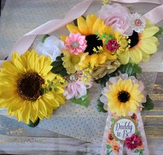 a bouquet of sunflowers and roses on a polka dot tablecloth with a card for daddy to be