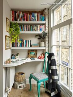 an empty room with bookshelves and a chair in front of the open window