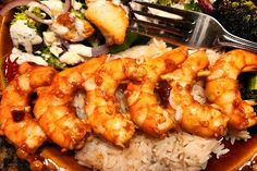 a plate with rice, broccoli and shrimp on it next to a fork