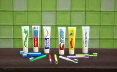 several toothpaste tubes lined up next to each other on a wooden table in front of a green tiled wall