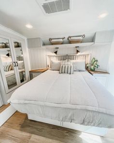 a white bed sitting inside of a bedroom on top of a hard wood floored floor