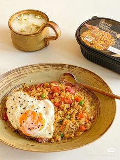 an egg is on top of rice in a bowl with a spoon next to it