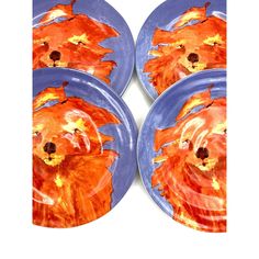 four plates with an image of a dog on them, all painted orange and blue