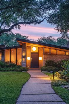 a house that is lit up at night with lights on the front door and walkway leading to it