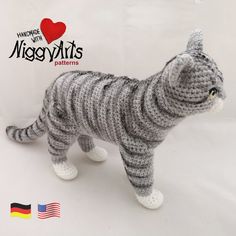 a crocheted gray and white cat standing on top of a white table next to an american flag