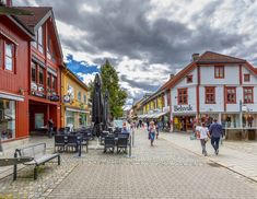 people are walking down the street in front of shops and buildings on a cloudy day