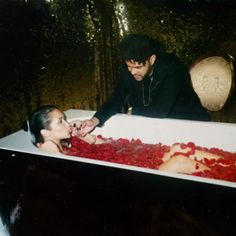 two people in a bathtub with rose petals on the floor