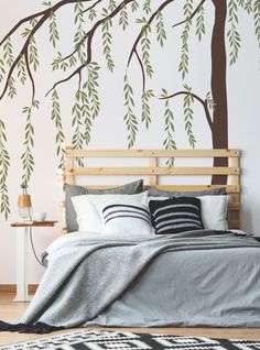 a bedroom with a tree wall decal on the wall and bed in front of it