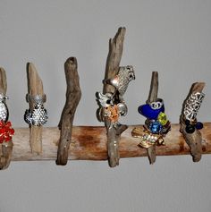 five different rings are sitting on a piece of driftwood that is hanging from the wall