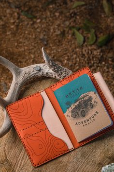 an orange and white wallet sitting on top of a tree stump next to antlers