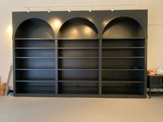 an empty bookcase in a room with several shelves on the wall and two lights above it