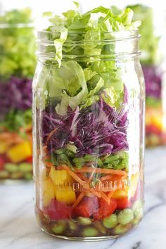 a jar filled with lots of different types of salads on top of a table