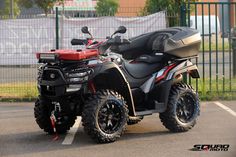 a black and red four wheeler parked in a parking lot next to a green fence