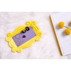 a yellow frame with black buttons on it sitting next to a book and some flowers