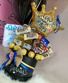 a basket filled with chocolates, candy bars and foil wrapped balloons in the shape of a crown