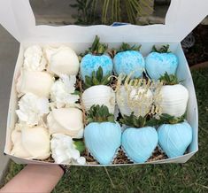 a box filled with lots of blue and white strawberries next to flowers on the grass