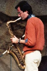 a man in an orange sweater playing a saxophone