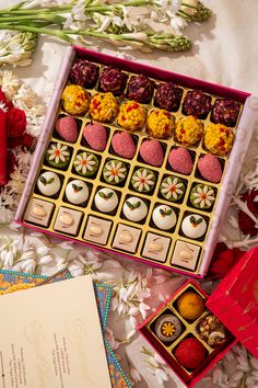 an open box of chocolates sitting on top of a table next to some flowers