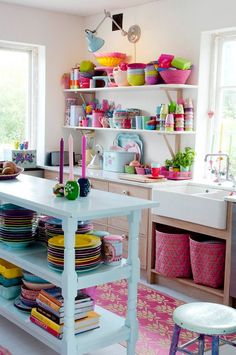 a kitchen filled with lots of colorful plates and bowls on top of a white table