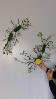 a person holding a yellow flower in front of a circular piece of art on the wall