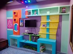 a colorful room with shelves, desk and television