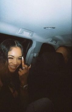 a woman is smiling while talking on her cell phone in the back of a car