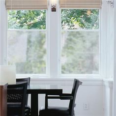 a table and chairs in front of two windows