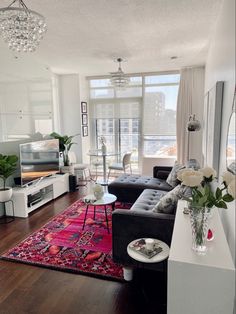 a living room filled with furniture and a large window next to a wooden floor covered in windows