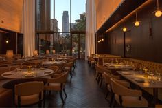 an empty restaurant with tables and chairs in front of large windows overlooking the cityscape