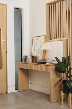 a wooden desk sitting in front of a door with a lamp on top of it