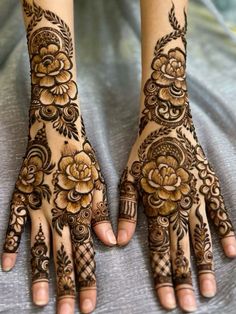 two hands with henna tattoos on them, one is showing the flowers and leaves