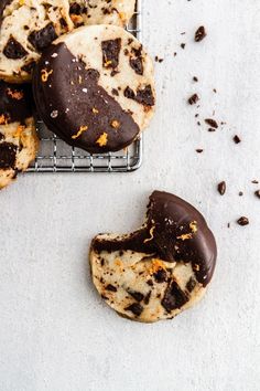 chocolate covered cookies on a cooling rack with orange peels scattered around them and one broken in half