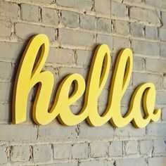 the word hello spelled in large yellow letters on a brick wall