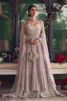 a woman in a wedding dress standing on a rug with flowers around her and wearing a tiara