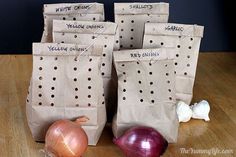 some onions and garlic sitting on a table next to two bags with writing on them