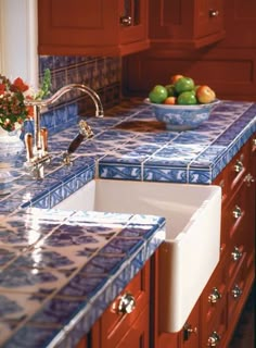 a bowl of fruit sitting on top of a kitchen counter next to an oven and sink