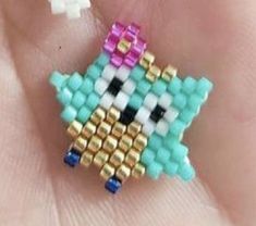 a close up of a person's hand holding a small beaded brooch