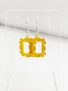 a pair of yellow earrings sitting on top of a clear acrylic display case