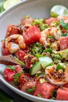 a white bowl filled with watermelon, shrimp and cucumber salad on top of a table