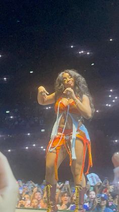 a woman standing on top of a stage in front of a crowd holding a microphone