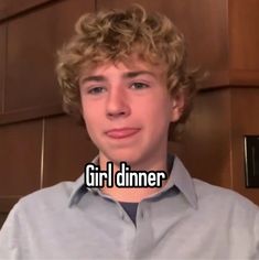 a young man with curly hair is looking at the camera and has an awkward look on his face