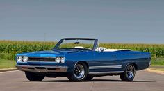 an old blue car is parked on the road in front of some cornfields