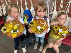 three children holding up bees made out of honeycombs