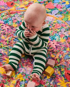 a baby laying on top of a colorful blanket covered in confetti and blocks