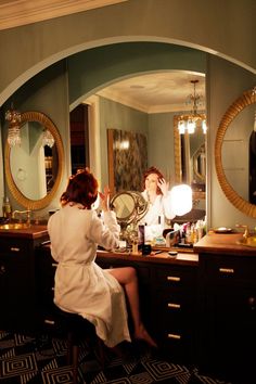 a woman sitting at a vanity in front of a mirror