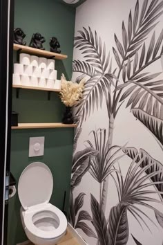 a toilet in a bathroom with palm trees on the wall